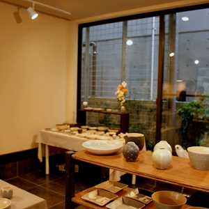 窓近くの自然光が陶芸や工芸の展示物を引き立てている写真